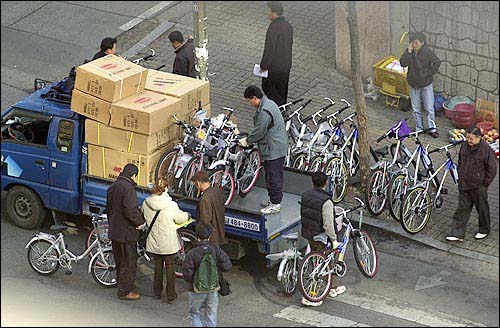 이제 구독을 위해 던지는 미끼가 '0개월 무료'에서 '자전거 경품'으로 바뀌었다. 지난 2003년 1월 20일 오후 서울 광진구 구의동 한 아파트 단지 입구에서 자전거 신문 판촉사원들이 트럭에 싣고 온 자전거를 내리는 모습. 